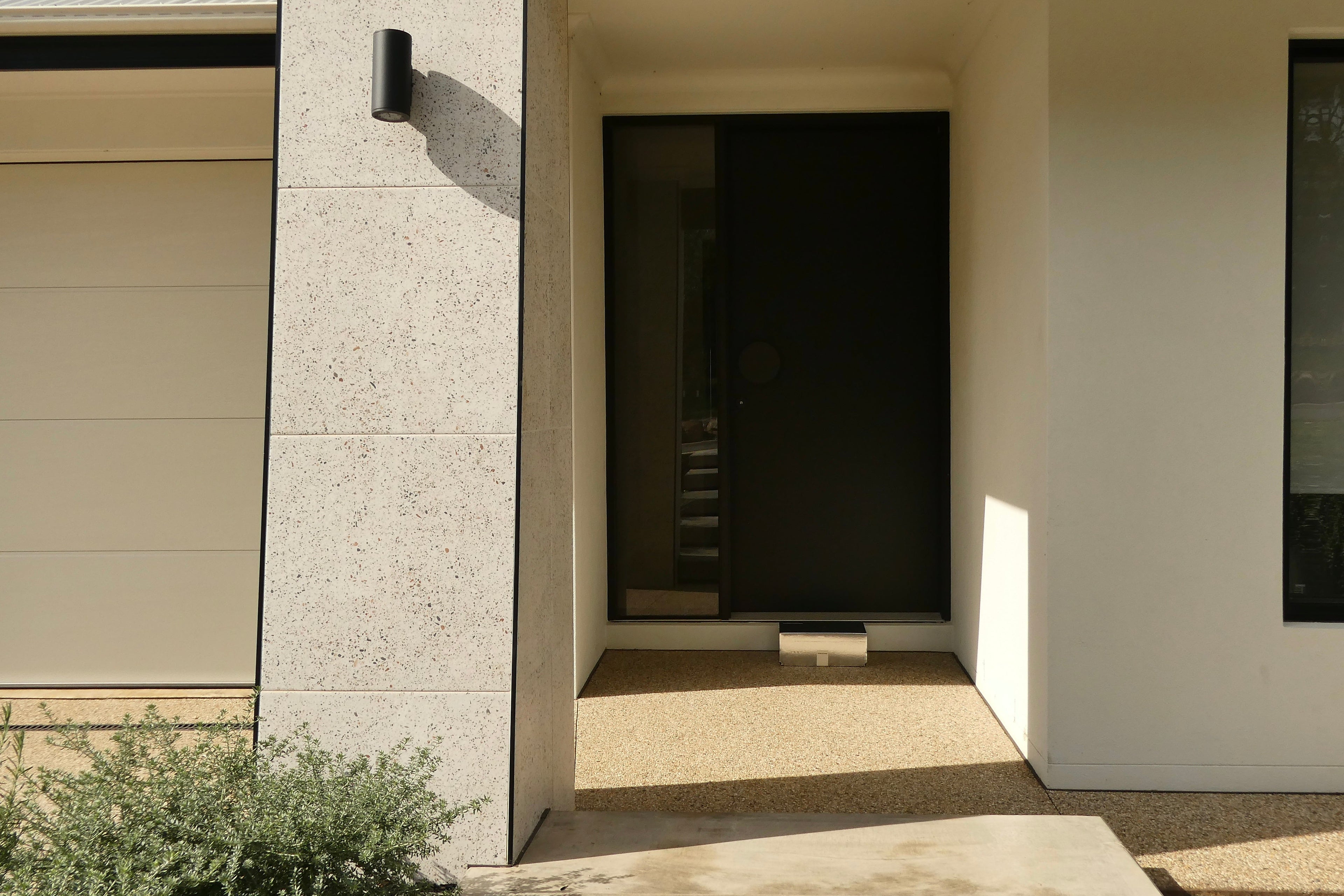 Delivery of a Fleur Kitchen ready made meal packaged in a disco box sitting at the front door of a modern house entrance with a light-colored exterior and dark door.